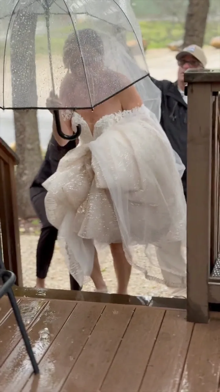 A planner holding an umbrella over a bride in the rain